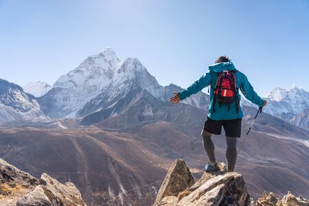Trail runner standing on top of mountain and looking to Ama Dablam mountain peak in Dingboche...