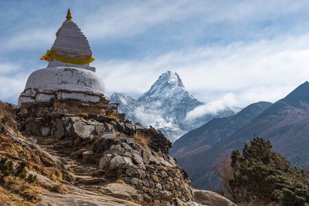 White traditional Tibetan stupa in front of Ama Dablam mountain peak in Everest base camp trekking route, Himalaya mountains range in Nepal, Asiaの写真素材