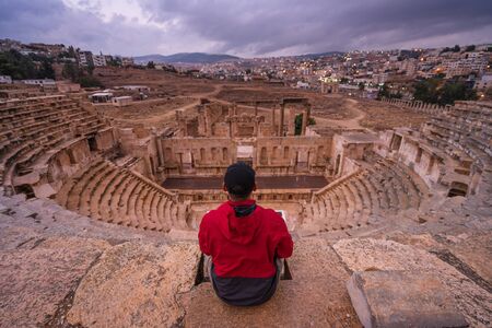 A man traveller sitting on top of Roman theater in Jerash ruin and ancient city of Roman empire in Amman city, Jordan, Arab, Asiaの写真素材