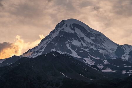 Sunset over Kazbeg mountain peak view from Kazbegi town, Caucasus mountains range in Georgia...
