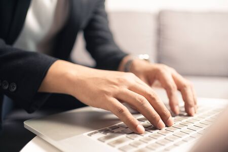 Close up hands of business man using laptop computer working from home sitting on sofa, new normal social distancing, work from home concept. Bangkok Thailandの写真素材
