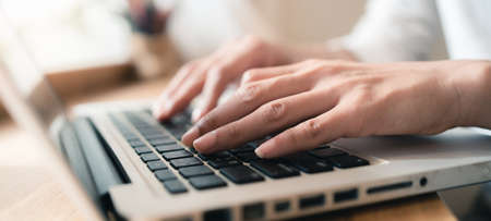 Close up hands of woman using laptop computer working and searching online information with blurry...