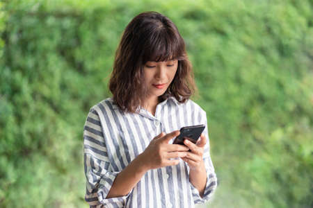 Young Asian woman chatting and searching with smartphone. A happy girl enjoying outdoor lifestyle...