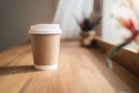Take away coffee cup with lipstick mark on wooden table in coffee cafe. Bangkok, Thailandの写真素材
