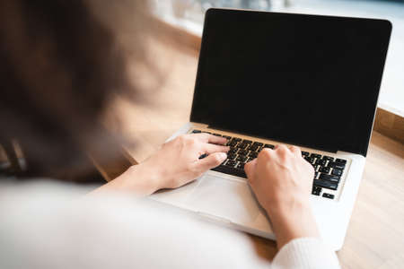 Close up hands of woman using laptop computer working and searching online information with blurry background. technology business and social distancing concept. Bangkok, Thailandの写真素材