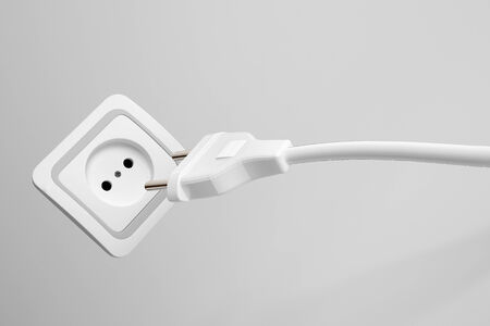Two prong plug, cord and electrical power outlet providing a supply of domestic electricity on a grey wall, not plugged inの写真素材