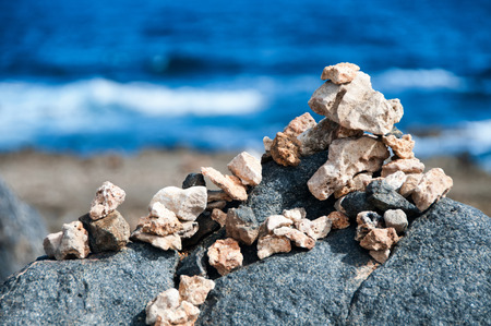 Small cairns and piles of pebbles at the seaside carefully balanced on the rocks overlooking the...