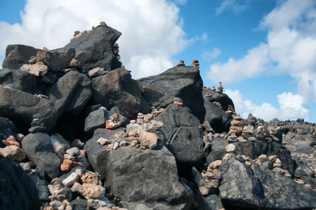 Stone pebbles stacked on the rocks on the beach in Aruba in a simple artistic statement of beaty in nature, zen and meditation under a sunny blue tropical summer skyの写真素材