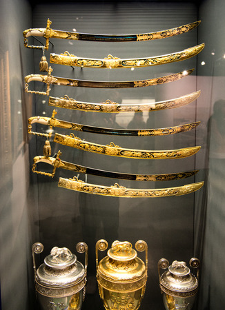 Museum Display of Gold Ornate Swords and Urns Behind Glassのeditorial素材