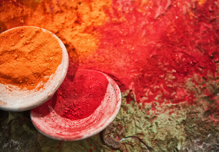 Spilled Orange and Red Powdered Pigment in White Bowls as seen from Aboveの写真素材