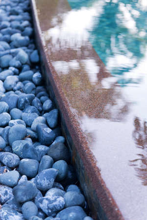 Close Up of Grey Stones at Edge of Swimming Pool in Tranquil Spa Settingの写真素材