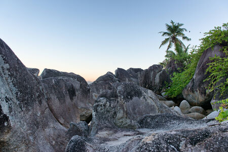 Close up Old Huge Rocks with Palm Tree Afar on Light Blue Sky Background. Located at Mahe Island, Seychelles.の写真素材