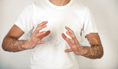 Close up Man in White Shirt Doing Conceptual Palm to Palm with Water Splash Effect on Off White Background.の写真素材