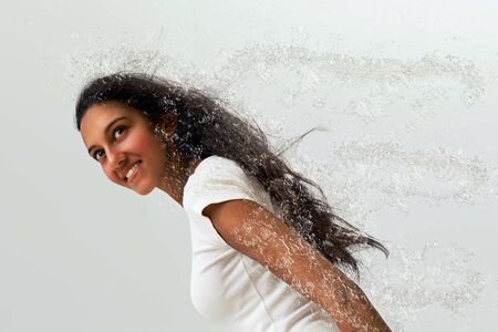 Close up Pretty Young Asian Indian Woman with Long Black Hair, Styled with Water Splash Effect on Light Gray Backgroundの写真素材