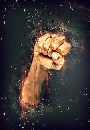 Man punching his fist through stones over a black background with in a dramatic conceptual imageの写真素材