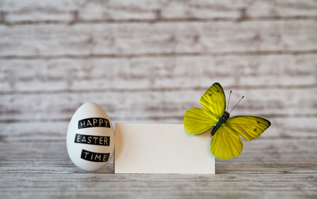 One White Chicken Easter Egg and White Blank Greeting Card with Colored Butterfly on the Upper Right...