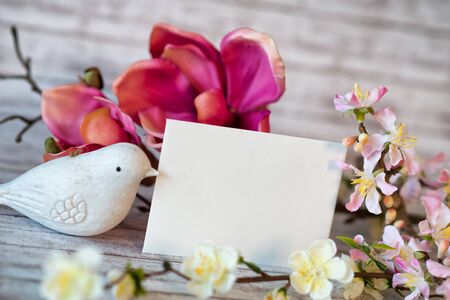 White Bird Figurine beside Blank Horizontal Card with Copy Space and Colorful Spring Blossoms
