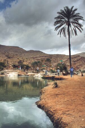 People Walking Around Edge of Wadi Bani Khalid with Dark Clouds Overhead, outside of Muscat, Omanの写真素材