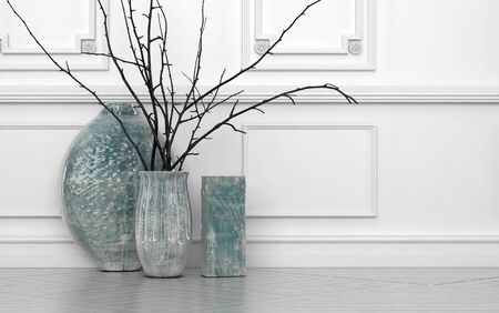 Modern arrangement of twigs in hand crafted ceramic vases of different shapes standing on the floor against a white paneled wall with copyspaceの写真素材