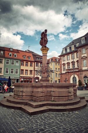 Stone statue of Hercules, hero in Greek mythology, on the central column of a decorative fountain under a dramatic cloudy sky, landmark from Heidelberg, Germanyのeditorial素材