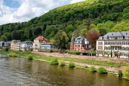 Historic buildings on the bank of the Neckar River in Heidelberg, Germany on the slopes of a forested hillのeditorial素材