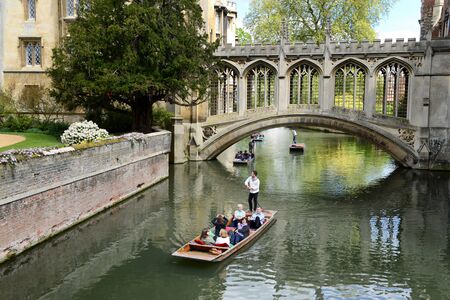 People punting on the Cam River, Cambridge, England passing under the Bridge of Sighs spanning the River between the Courts of St Johns University Collegeのeditorial素材