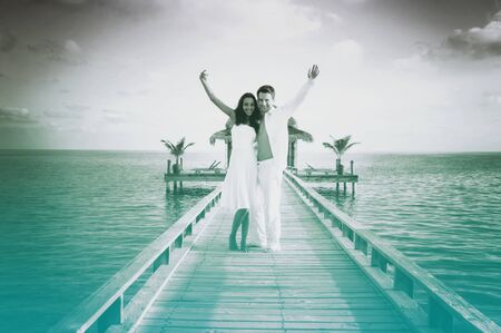 Sensual love couple on a jetty on Maldives. Grayscale picture with azure color accent.の写真素材