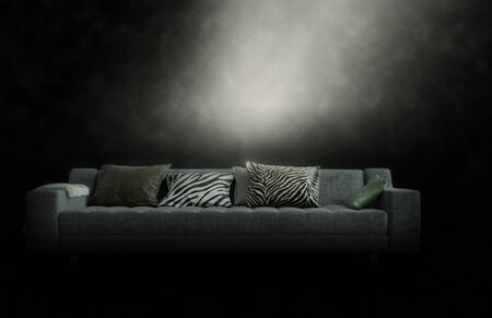 Large three-seater couch with cushions in a gloomy smoky atmosphere illuminated from above by a ray of light, with copyspaceの写真素材