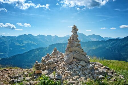 Manmade Cairn Rock Structures Overlooking Picturesque Mountain Range on Bright Sunny Day with Blue Skyの写真素材