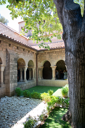 Arched stone colonnade and courtyard surrounding a small garden and tree on an old historic building in Espanyol Poble, Barcelona, Spainの写真素材