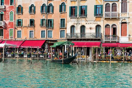 Colorful open-air restaurants with red canopies in front of the Hotel Marconi on the Grand Canal, Venice in the region of the Rialto Bridgeのeditorial素材