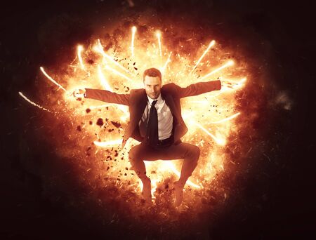Businessman bursting through a wall of fire with flying explosive sparks in a conceptual image of...