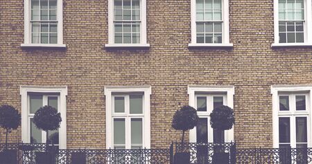 Old brick building with topiary trees displayed on the open air balcony with an ornate wrought iron...