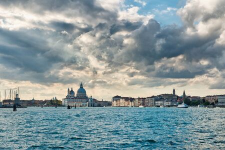 View down the Giudecca Canal, Venice, Italy towards the Basilica Santa Maria della Salute with San Georgio Maggiore on the left on a stormy cloudy dayの写真素材