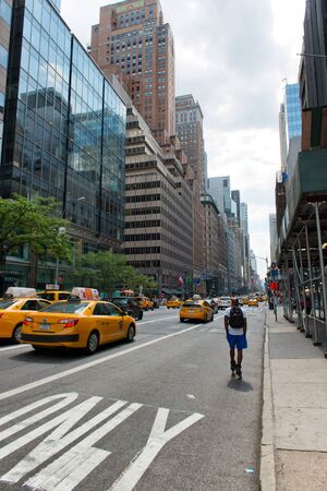 Rear View of Man Rollerblading on Street Amongst Yellow Taxi Cabs on Busy City Street in New York City, New York, USAのeditorial素材