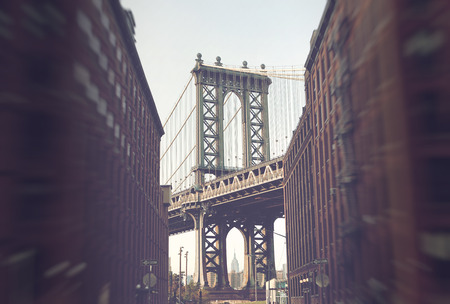 Manhattan Suspension Bridge as seen from Street Level Between Low Rise Apartment Buildings with Traditional Architecture and View of New York City Skyscrapers in Background, New York, USAの写真素材