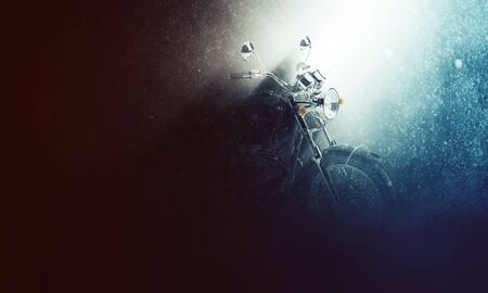 Motorbike in a rainy stormy atmosphere backlit by a shaft of light illuminating the handlebars in...