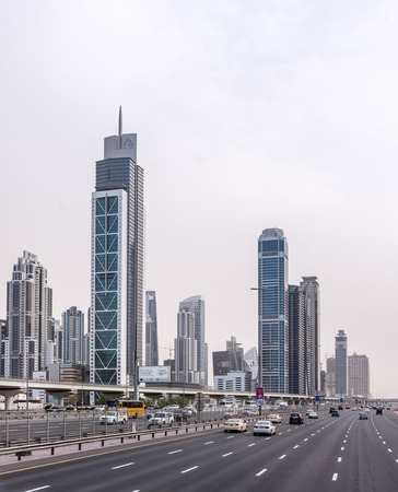Traffic on a multi lane motorway in Dubai, UAE driving past modern skyscrapers and architecture on a cloudy dayのeditorial素材