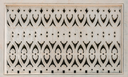 Decorative intricately carved white marble panel in a traditional Arabic design in a close up view of an architectural detailの写真素材
