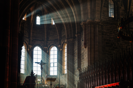Dark church interior with crucifix above altar as light pours in from nearby arched windowsのeditorial素材