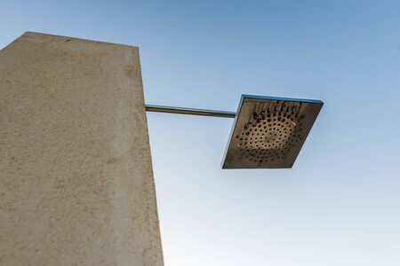 Low angle view on lamp or watering object connected to concrete wall with blue sky in backgroundの写真素材
