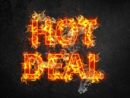 Hot Deal advertising poster with burning letters engulfed in fiery orange flames and showering sparks on a black backgroundの写真素材