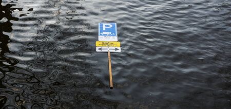 Parking road sign with leg stick floating on wavy surface of water in canal of Amsterdamの写真素材