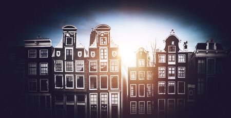 Front view of traditional Amsterdam buildings with glowing warm light and dark oval vignette effectの写真素材