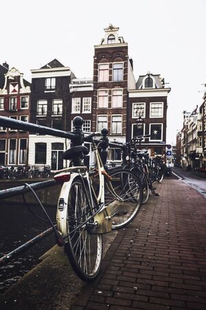 Close up low angle view of old bicycle tied to bridge railing in Amsterdam, Netherlandsの写真素材