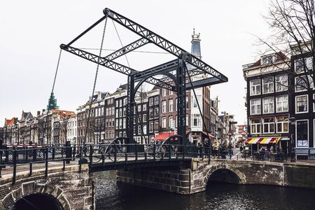Drawbridge or bascule bridge on canal with metal mechanism side view in cloudy day - Amsterdam, Netherlandsのeditorial素材