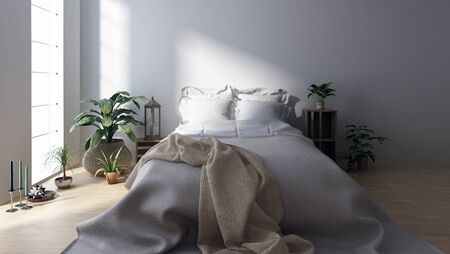 Double bed with blanket in bright minimalist bedroom among houseplantsの写真素材