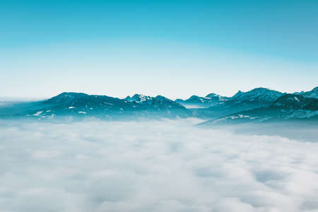 Minimalist cloudy atmospheric landscape with distant mountain peaks visible in the background above a layer of white cloudの写真素材