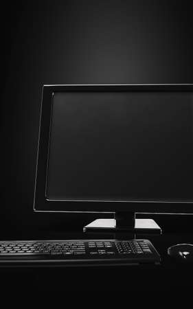 Dark trendy modern luxury monochrome workstation with black decor furnished with a matching black desktop monitor, keyboard and mouse. 3d renderingの写真素材