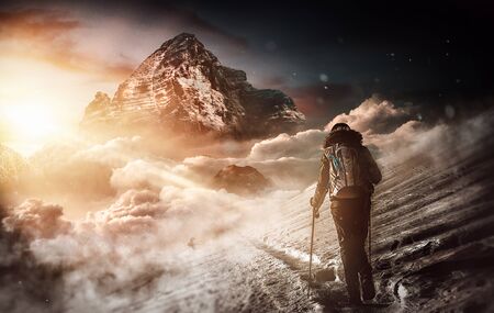 Fit woman hiking through a frozen winter landscape along a narrow trail through the snow towards a...